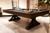 Otis Slate Pool Table by Plank & Hide in Smokehouse finish, shown in a 3/4 angled lifestyle shot at High Point Market in North Carolina, featured in a designer trade show setting with professional lighting and styled vignettes to highlight its modern farmhouse appeal and craftsmanship