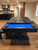 Otis Slate Pool Table by Plank & Hide in Smokehouse finish, styled in a high-end residential space with half of the optional dining top installed, revealing the Euro Blue felt playfield beneath; shown with elegant home décor and soft natural lighting to highlight the table’s dual-purpose versatility