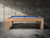 The Paula Parsons pool table by Doc & Holliday displayed in a luxury concrete loft setting, finished in Glazed Maple with vibrant Academy Blue felt. A modern parsons design perfect for high-end entertainment spaces and designer interiors.