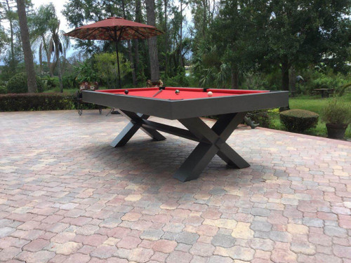 The X-Air 8' Outdoor Custom Slate Pool Table positioned on a spacious outdoor patio, showcasing its durability and modern design. The table features stainless steel hardware and is complemented by the natural surroundings, perfect for luxurious outdoor entertainment.