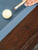 Close-up of the Portland Slate Pool Table’s rail, showcasing the distinctive black hammered diamond-style billiard sights set against the rustic hardwood finish. These matte-finished inlays offer a subtle, modern-industrial detail that complements the table’s black X-leg steel base while providing practical visual alignment for accurate gameplay. Photographed in soft ambient light, this detail shot captures the understated craftsmanship and elevated aesthetic Nixon Billiards is known for—exclusively available through Sawyer Twain.