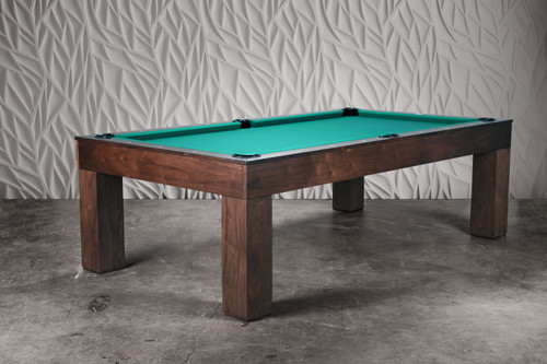 The Paula Parsons Slate Pool Table is styled in a refined game room setting, shown from a ¾ angle to highlight its clean Parsons silhouette. The Natural Walnut finish brings warmth and texture to the space, complemented by neutral décor and soft ambient lighting. The table feels like an intentional design piece—both functional and artful.